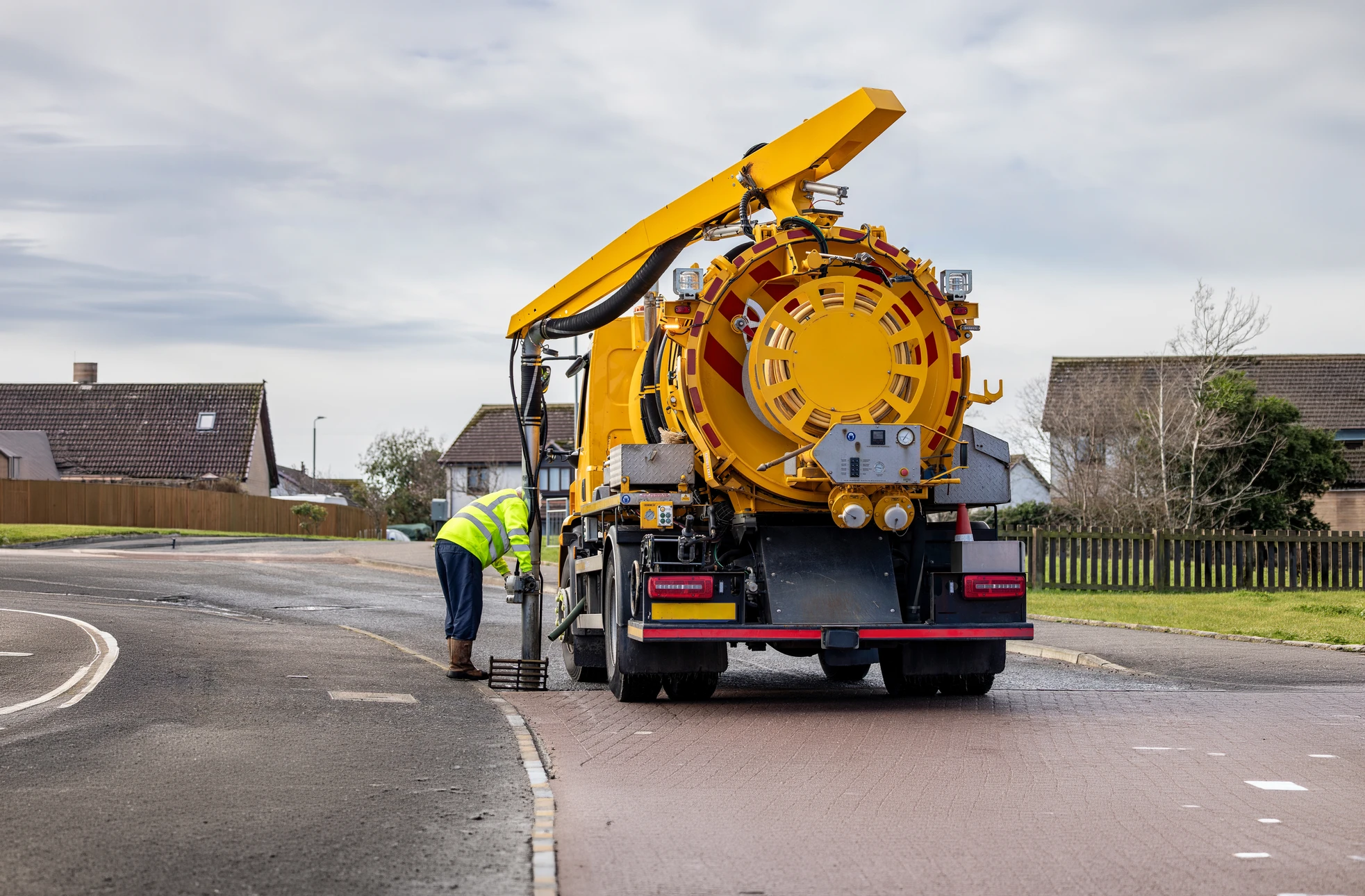 Scène extérieure de lavage automobile avec véhicule berline sombre aspergé par jet d'eau haute pression