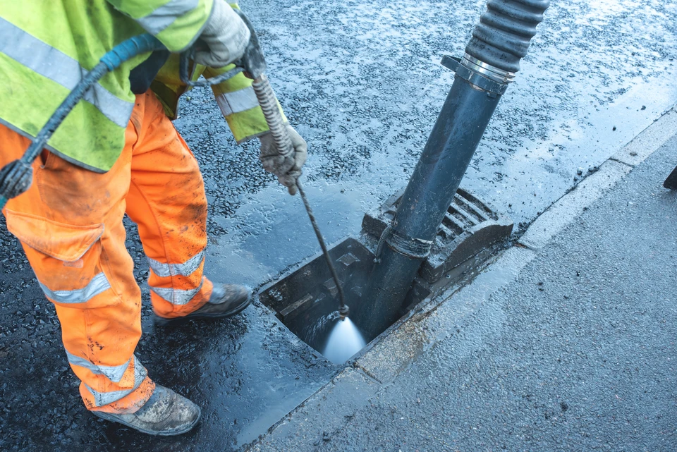 Employé en tenue de travail utilisant une monobrosse professionnelle sur sol carrelé dans un hall d'immeuble moderne