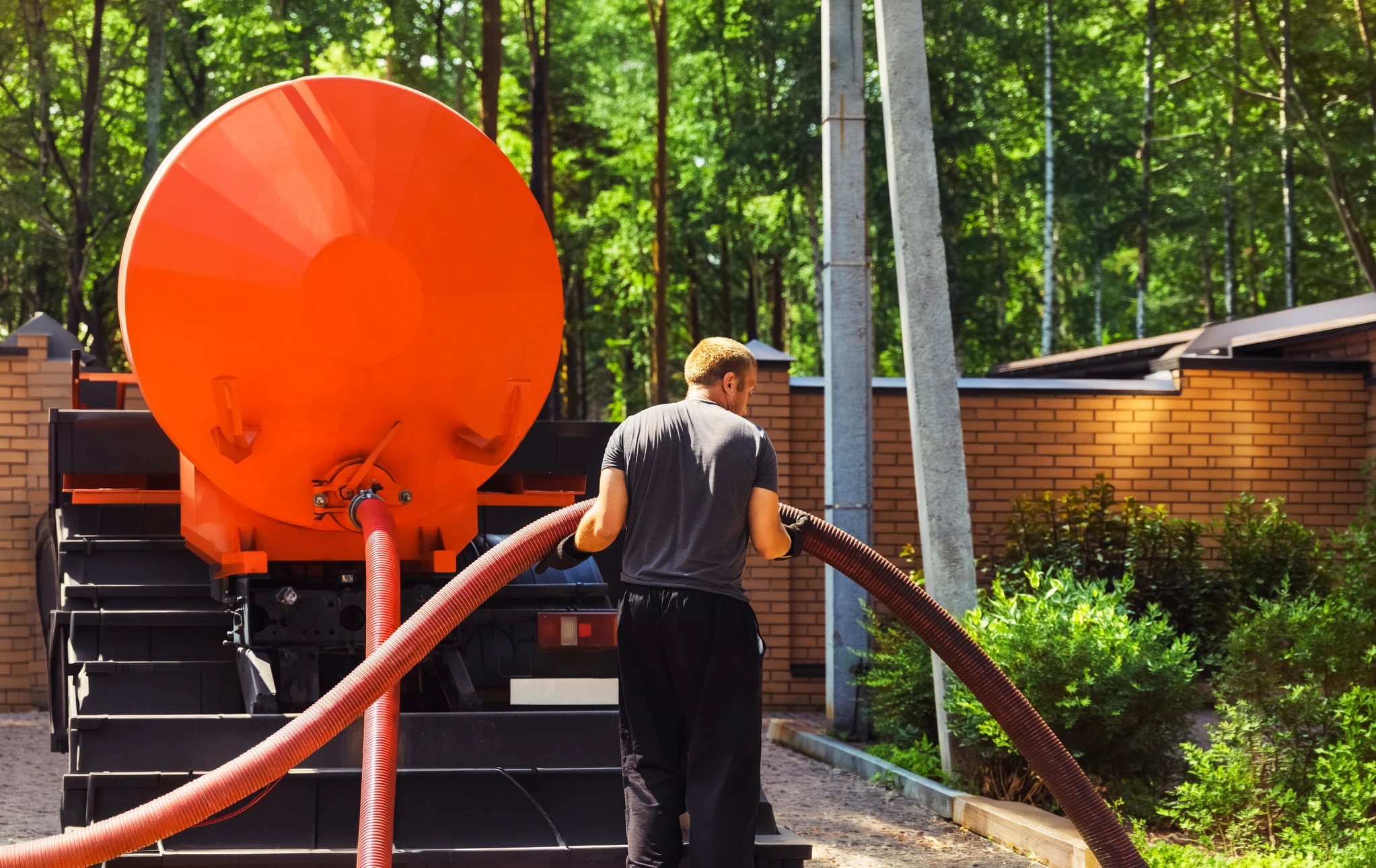 Mécanicien effectuant une vidange d'huile moteur sous un véhicule surélevé dans un garage automobile